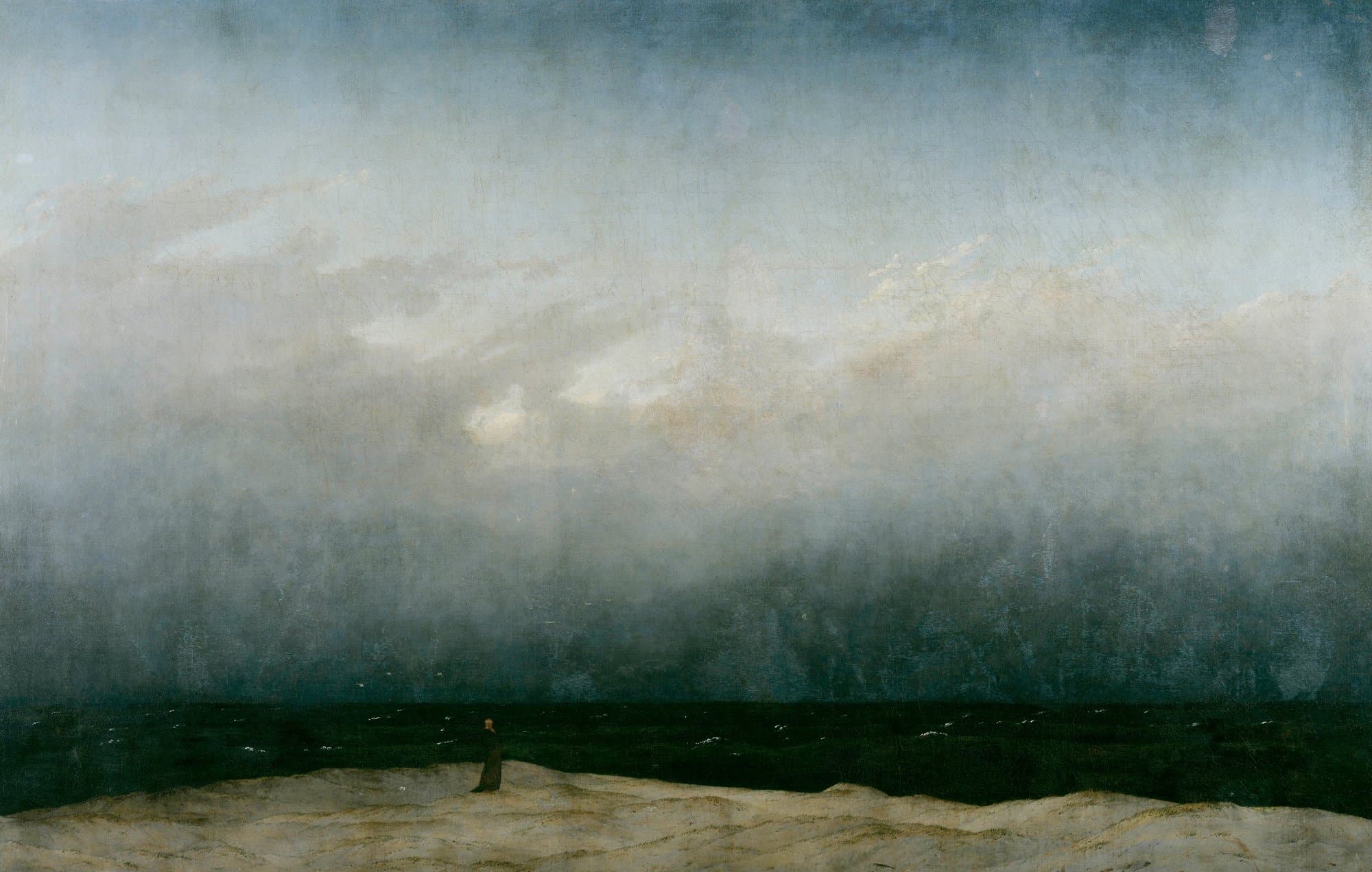 A painting of a lone figure in a dark robe standing on a pale strip of dune before a black-green sea, under a vast grey sky that fills most of the canvas.