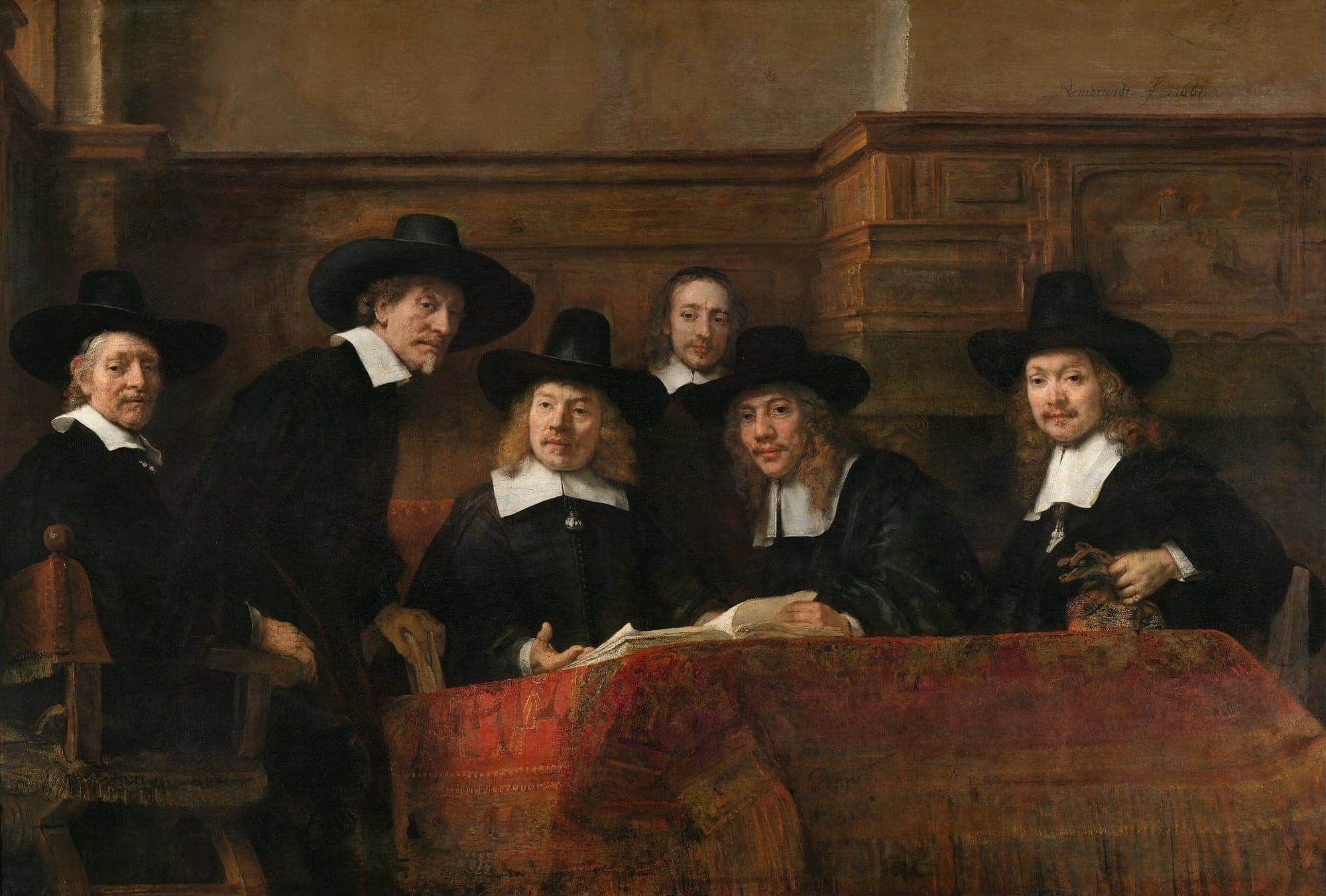 Six men in black with white collars, five of them in tall black hats, gathered behind a table covered with a deep red patterned carpet. The seated man at the centre has an open book before him, and one man rises from his chair as they look out of the picture. Wood panelling runs behind them.