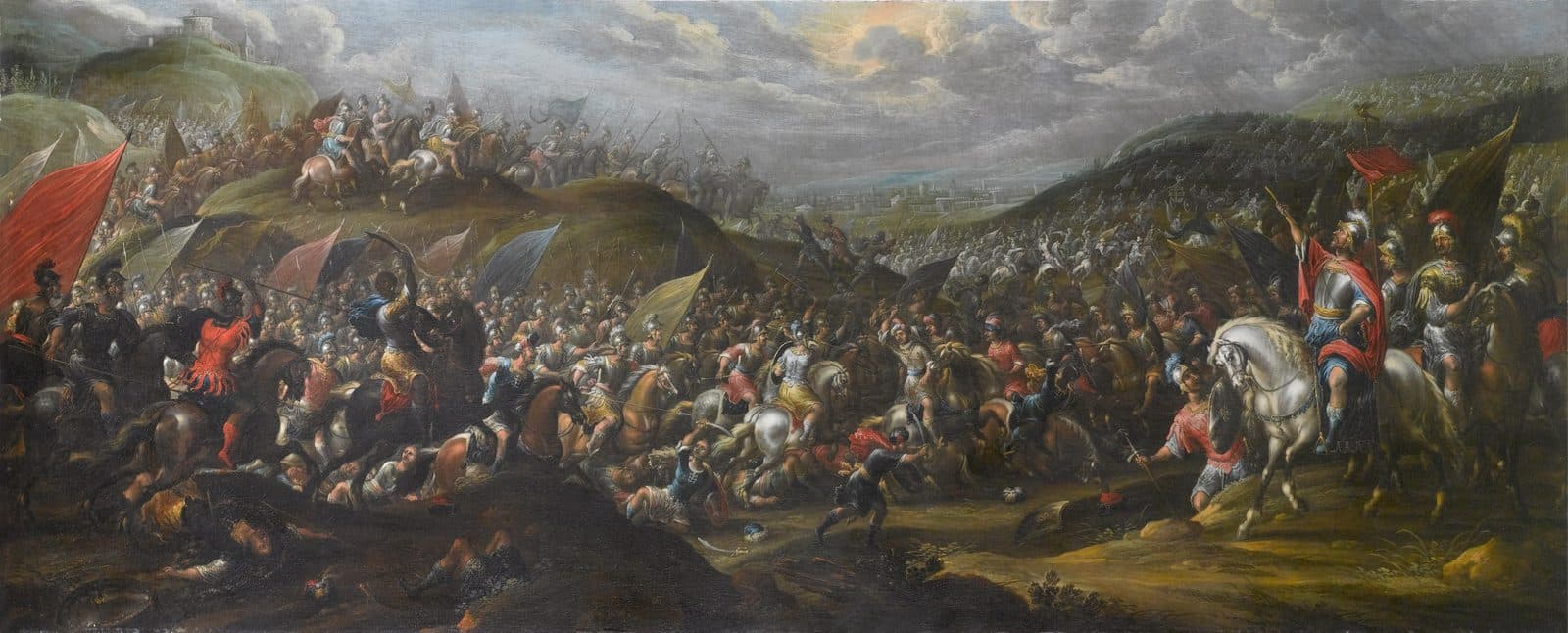 A wide battle on hills under a stormy sky: on the right Joshua in red and armour sits on a white horse with his arm raised toward the sun breaking through the clouds, while horsemen and soldiers with red, gold and blue banners clash across the slopes and a walled city lies in the distance.