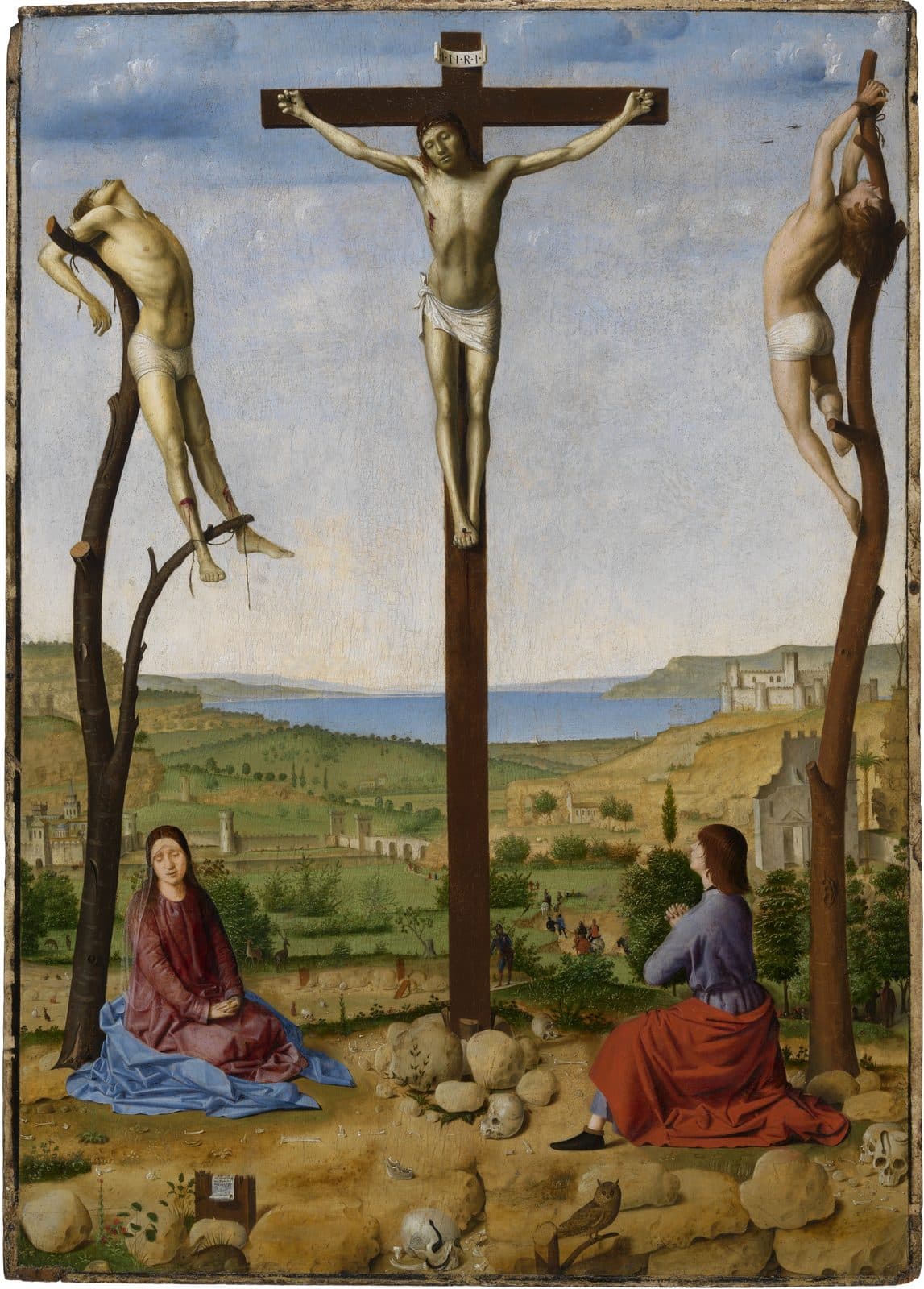 Christ hangs on a tall cross between the two thieves, who are bound to the trunks of bare trees, while Mary sits with her eyes lowered and John looks up with his hands clasped, on stony ground strewn with skulls before a wide valley, walled towns and a bay.