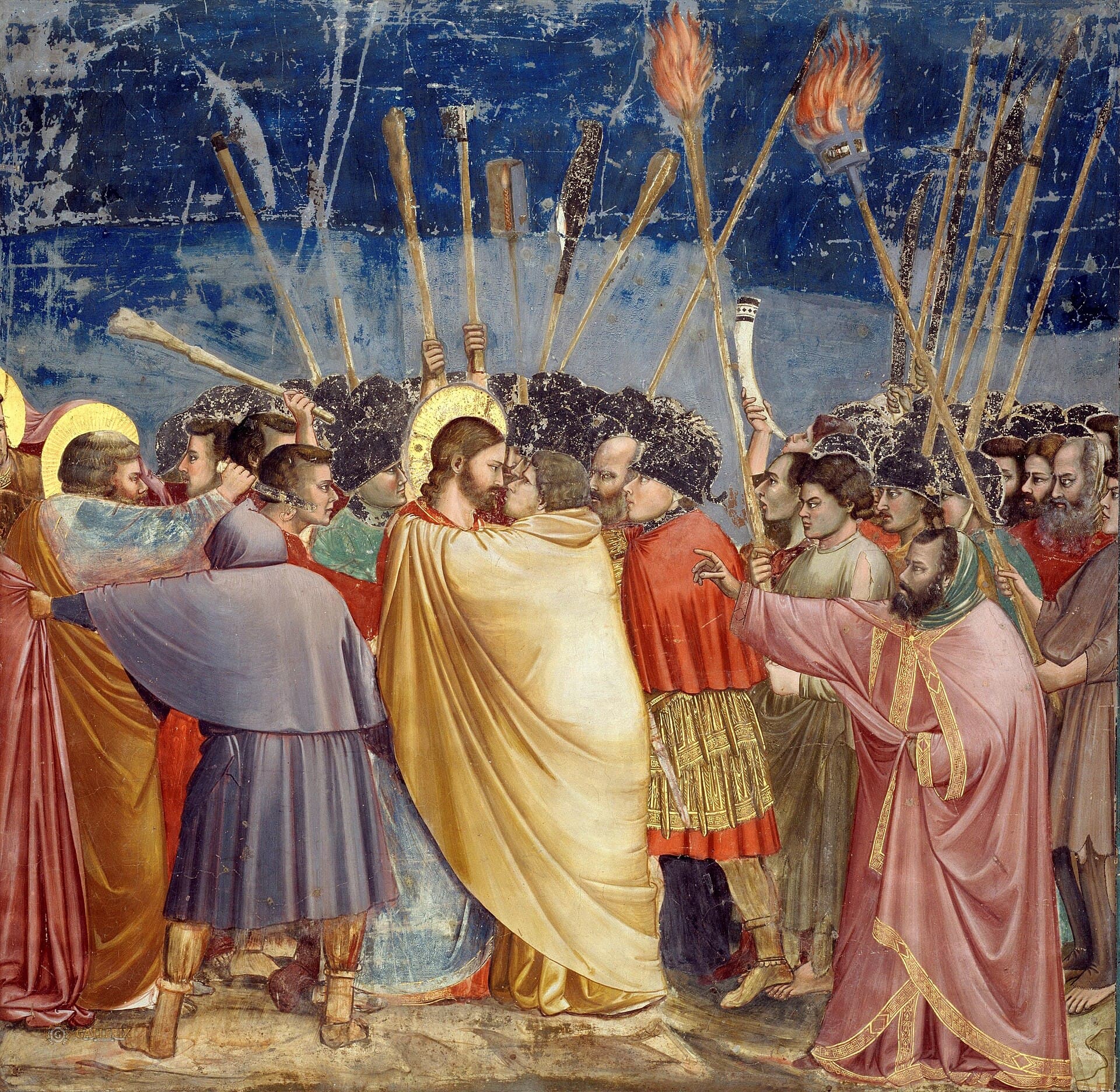 Under a deep blue night sky full of raised torches, clubs and spears, Judas in a yellow cloak wraps his arms around Jesus and leans in to kiss Him while they look into each other's faces, and a crowd of soldiers presses around them as a man in a rose robe points at Jesus.