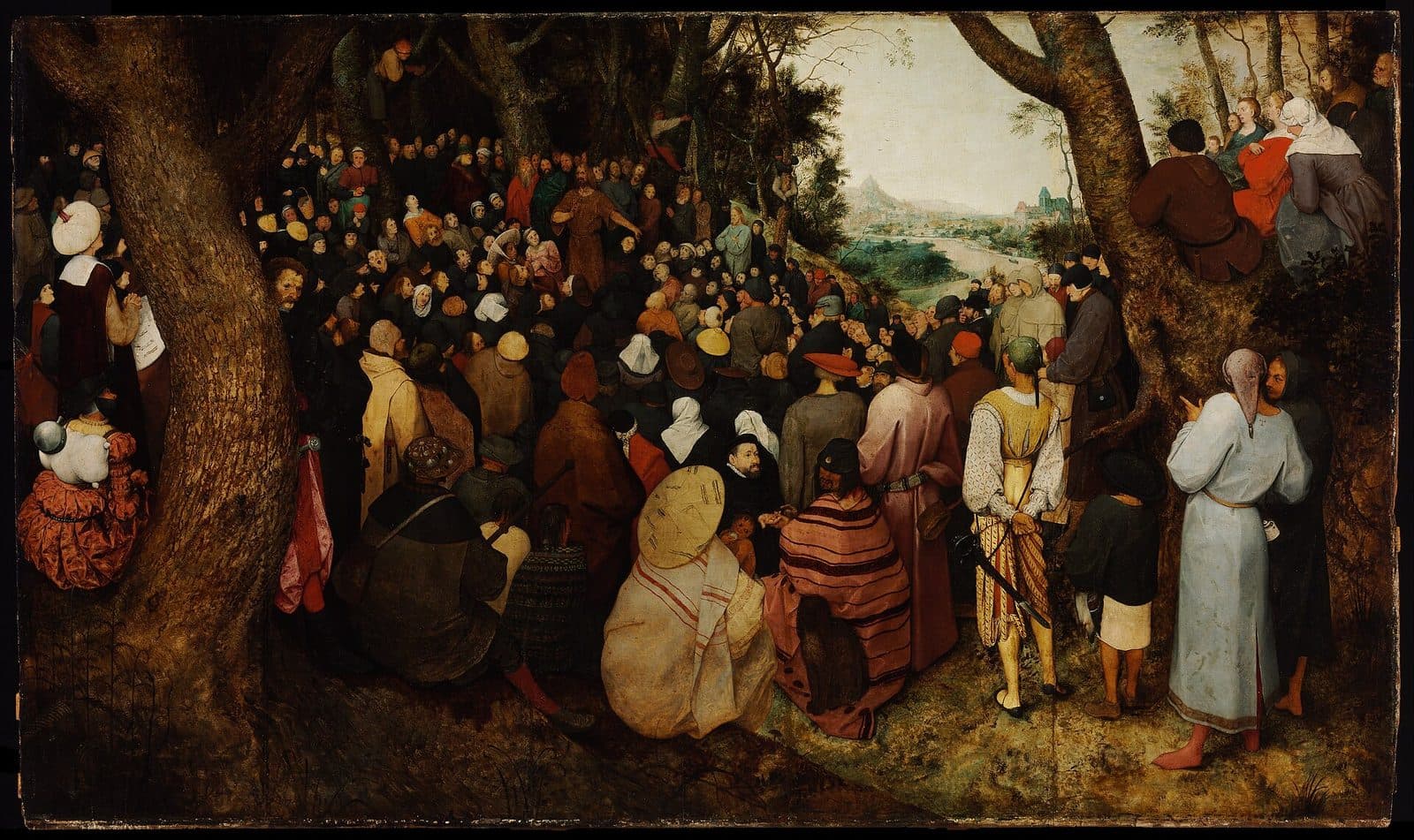 Pieter Bruegel the Elder's painting of a great crowd in sixteenth-century dress filling a forest clearing, listening to a preacher in brown who stands far back among them, with a river valley beyond the trees