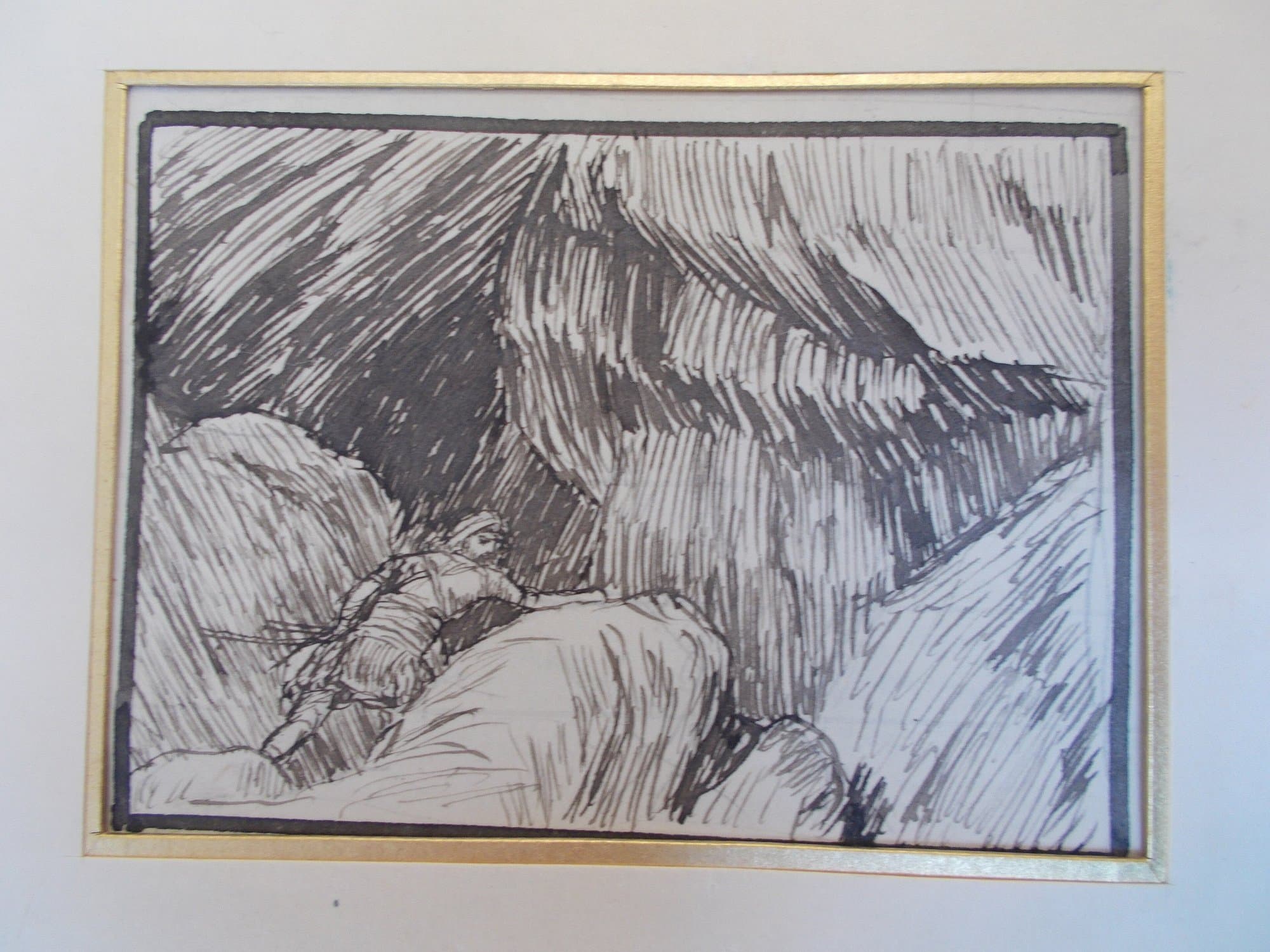 A pen and ink sketch of a man in a head covering climbing over rocks into the dark mouth of a cave, drawn in close hatched lines inside a gold mount.