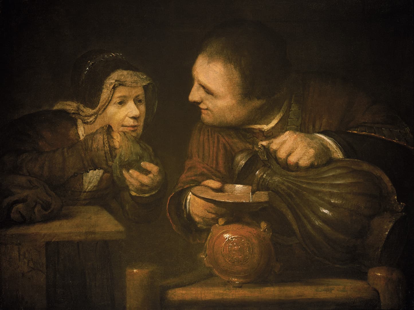 In a dark room a young man in a red coat smiles as he tips a large bulging flask and pours oil into a shallow dish above a round red jar, while an old woman in a white headscarf and dark hood leans on a wooden ledge beside him holding a small green glass bottle.