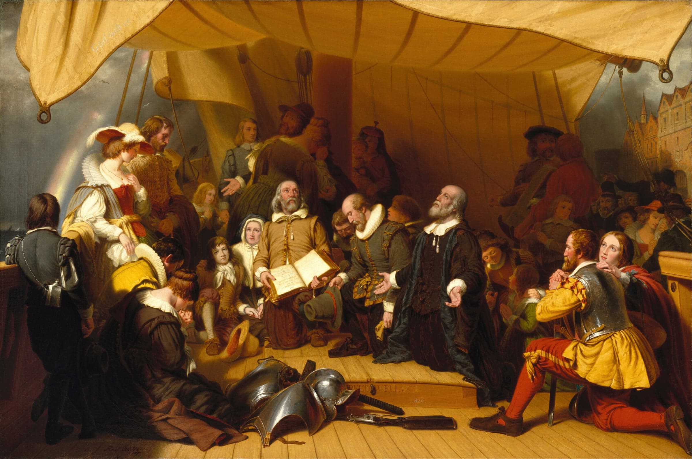 A painting of Pilgrims on a ship's deck under a sail awning, kneeling and standing in prayer around a minister with raised hands and an elder holding an open Bible.