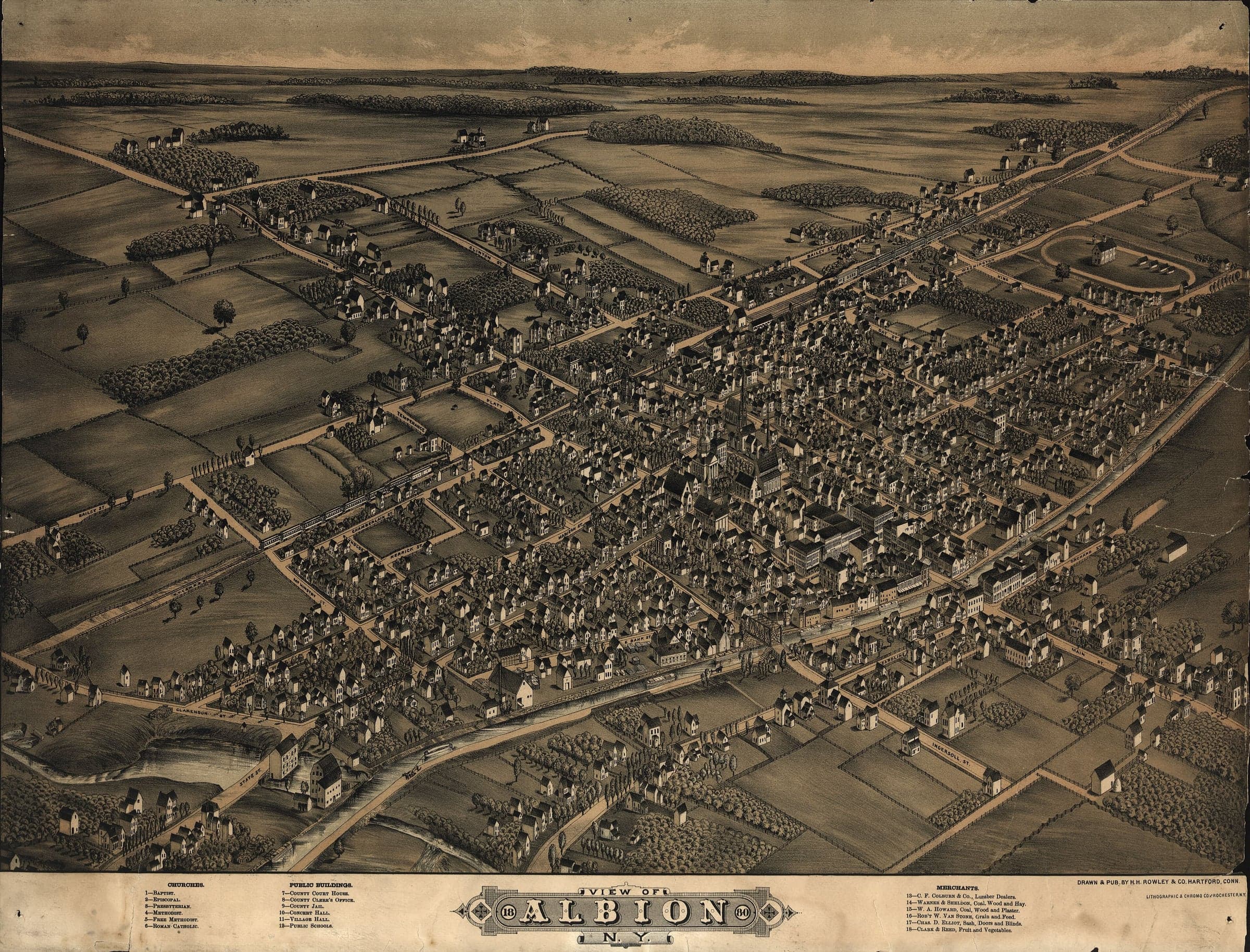 A bird's-eye view of a small town on a grid of tree-lined streets, with a canal and a railway crossing it among open fields.