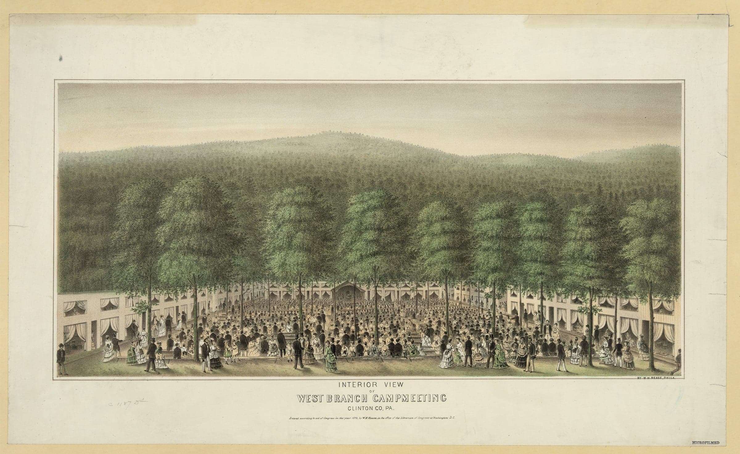 A crowd sits on benches under tall trees before a preaching stand, ringed by rows of curtained tents, with wooded hills behind.