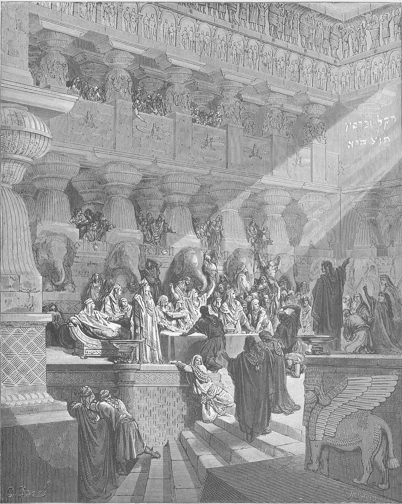 A vast columned hall of Babylon with carved friezes and stone elephants. A shaft of light falls on Hebrew letters high on the right wall, a dark-robed man stands pointing up at them, and the king and his guests at the banquet table turn toward him.