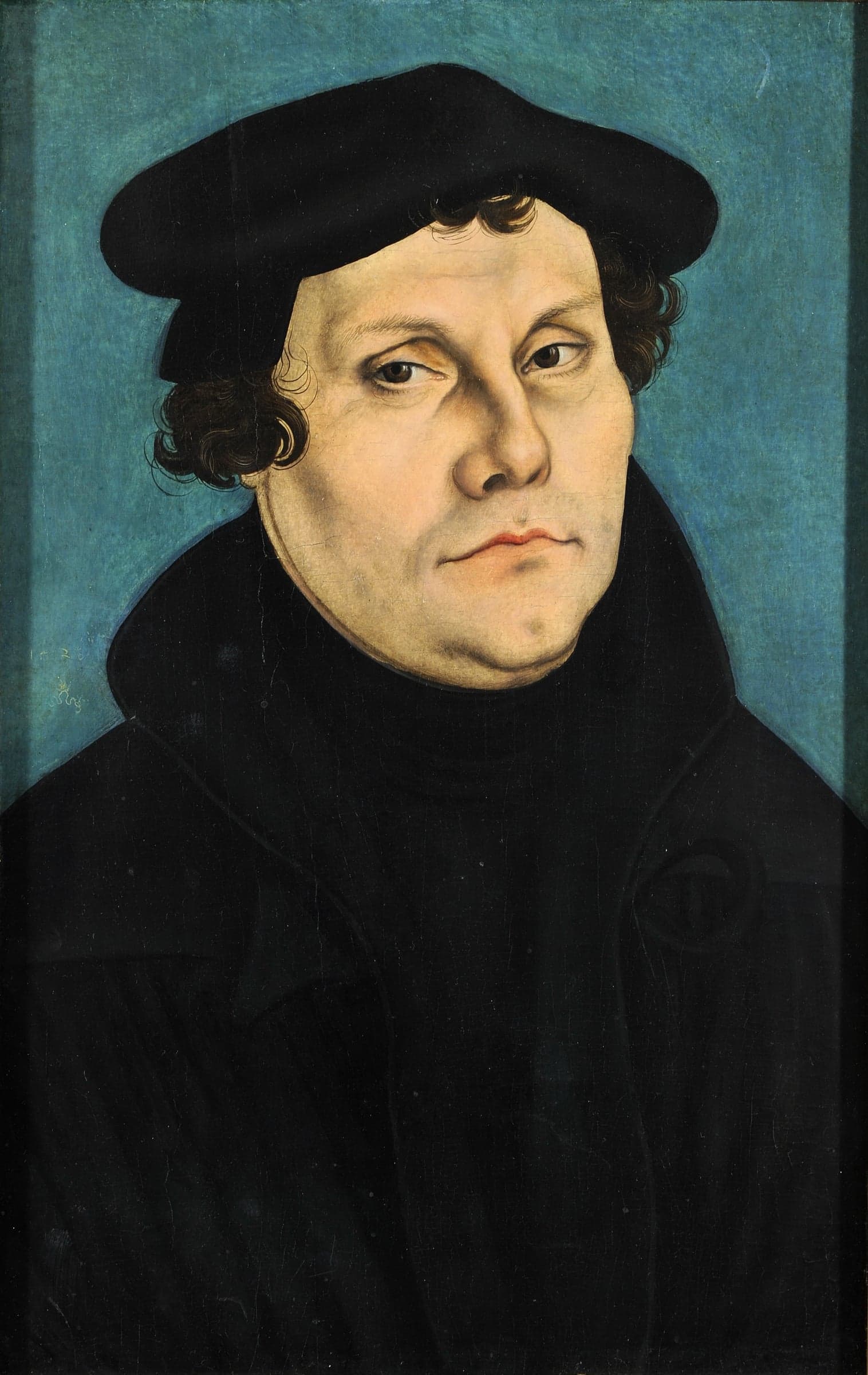 Martin Luther, half length against a plain blue ground, in a black gown and cap, his hands folded at his waist.