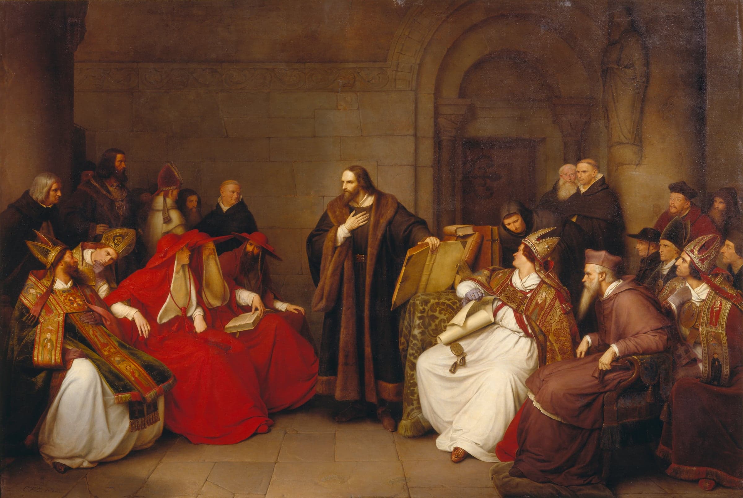 Jan Hus, in a dark fur-trimmed robe, stands with a hand on his breast beside an open book, facing cardinals in red and bishops in mitres.