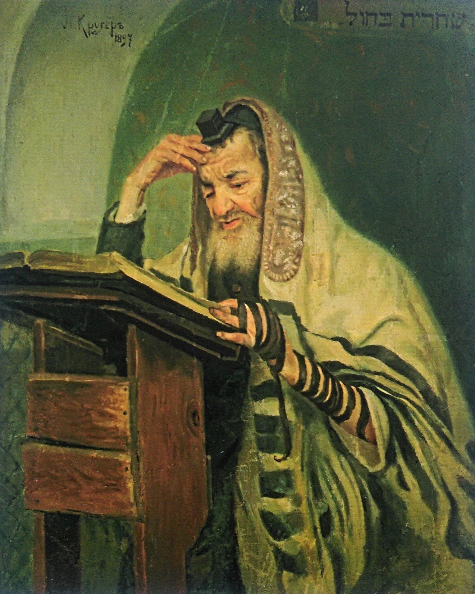 An old bearded man wrapped in a striped prayer shawl leans over a wooden lectern with an open book, a small black box bound on his forehead and black leather straps wound down his left arm, one hand pressed to his brow.