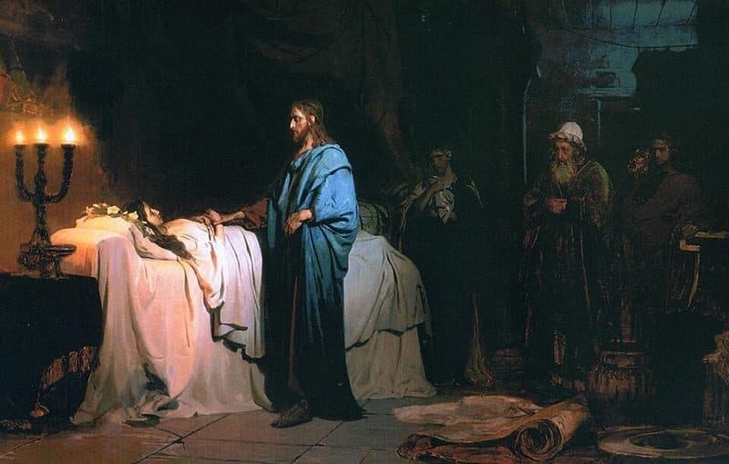 A dim room lit by three candles, where Jesus in a blue cloak stands beside a bed and lays His hand on a girl lying under a white sheet, while an old man in a white turban and others watch from the shadows.