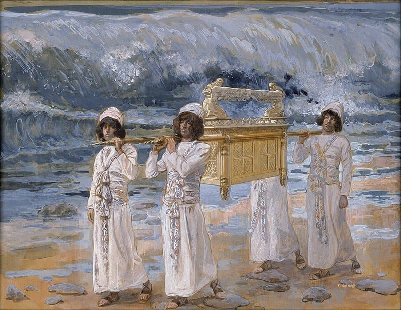 Priests in white robes carry the golden ark on poles across the dry bed of the Jordan, with a crowd of Israelites following behind them and the river held back in a wall of water at the right.