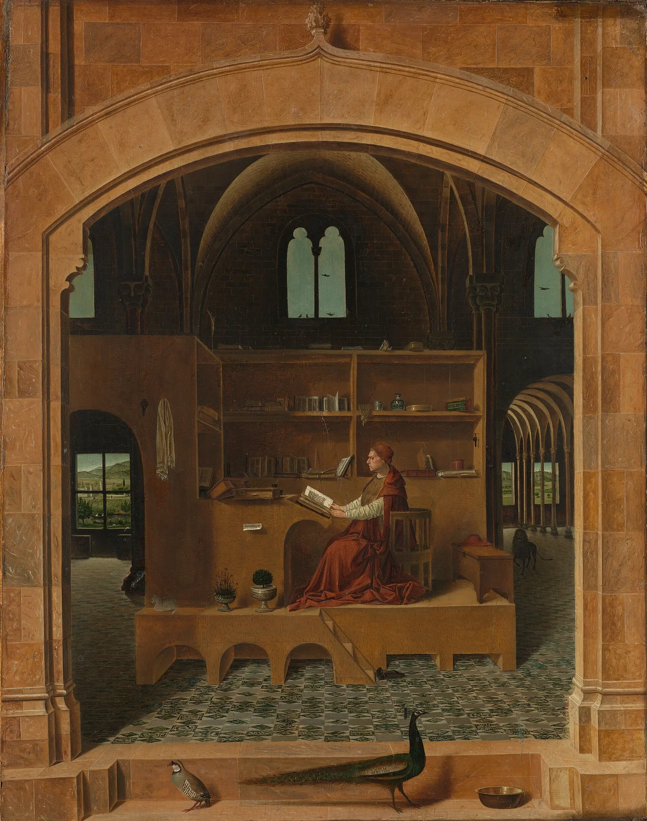Jerome in a red robe sits reading at a raised wooden desk inside a great stone hall seen through an arch, with shelves of books around him and a peacock on the ledge in front.