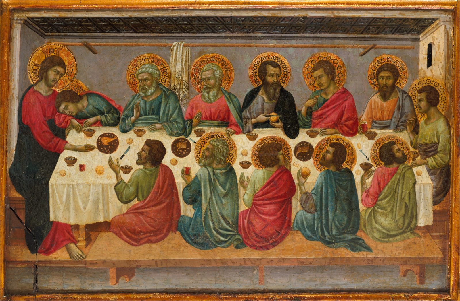 Jesus stands at the left end of a long table with a young disciple asleep against Him; six apostles sit behind the table and five kneel before it