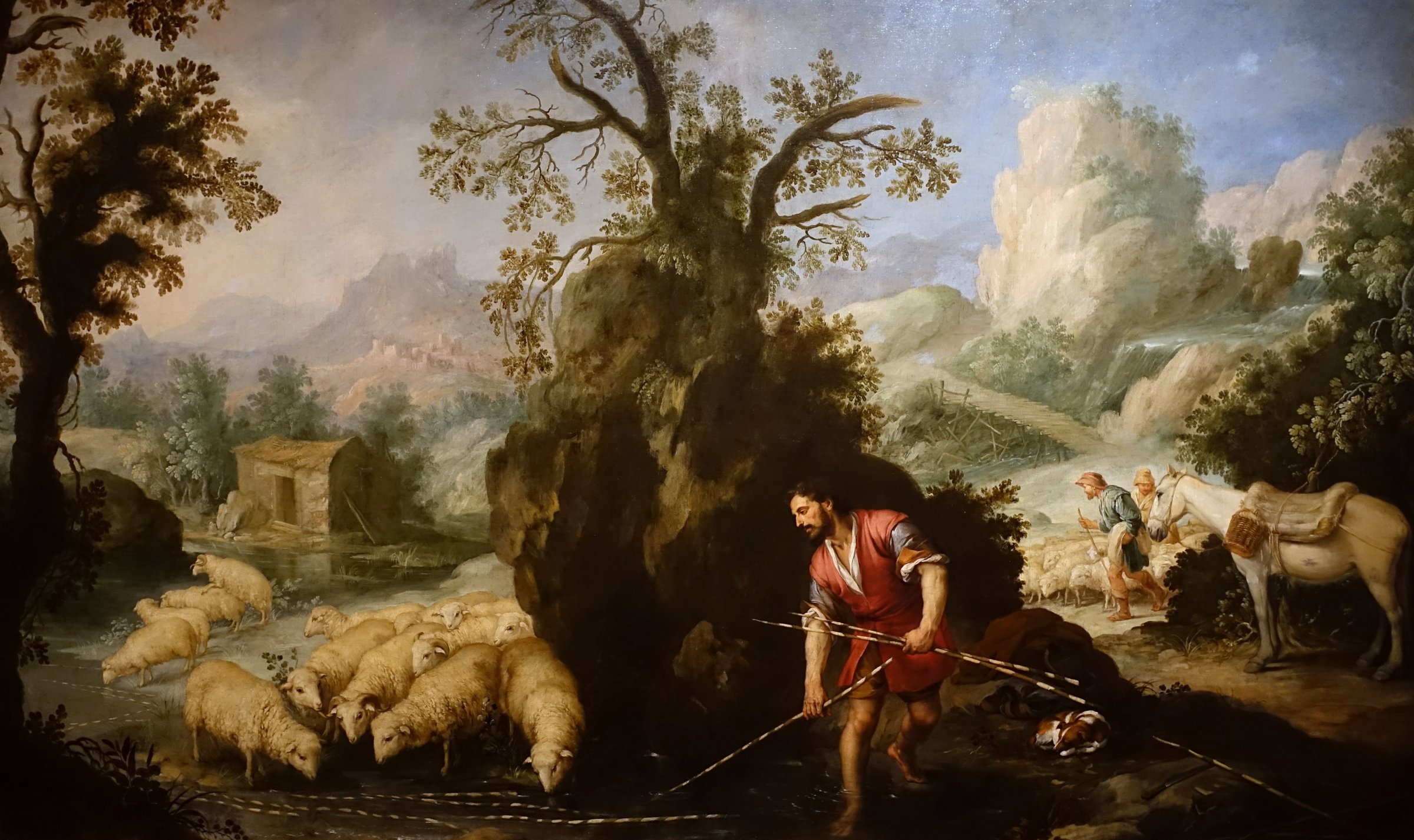 Jacob Laying Peeled Rods before the Flocks of Laban by Murillo: a man in red lays striped branches in a stream as sheep drink and herdsmen bring more of the flock down a path